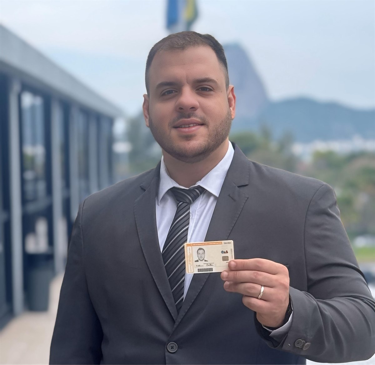 Arthur Chelles com sua carteira da OAB, com o Rio de Janeiro ao fundo